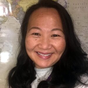 A headshot of Loan Nguyen wearing a light gray mock turtleneck sweater and silver necklace.